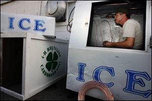 Todd Poupard makes repairs to a refrigeration line of an ice cooler before the opening of the county fair.
