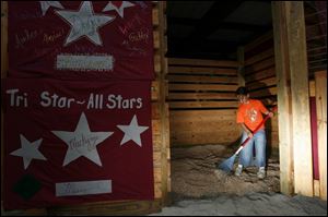 Almo, 8, rakes out wood shavings as she prepares a stall for a horse at the Monroe County Fair, which opens tomorrow. 