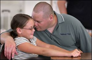 Julie Lee, 9, of Appleseed Ridge Girl Scout Troop 884, gets a hug from her dad, James Lee, an inmate at the prison.