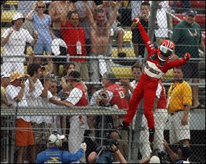 Helio Castroneves tacks on his signature victory celebration by climbing the fence at Michigan International Speedway after the Firestone 400. 