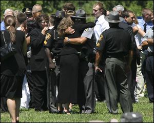 Mourners comfort each other during services at Springfield Township Cemetery for Holland police Chief Doug Kaiser.
