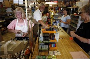 Diane Hudson, left, rings up a sale, as her husband, Bill, bags items for customers at their Cygnet grocery and carryout.
