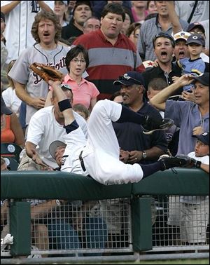 Tigers third baseman Brandon Inge goes into the stands and head over heels to catch a foul pop off the bat of the Indians' Victor Martinez. Detroit won despite a short night's rest.