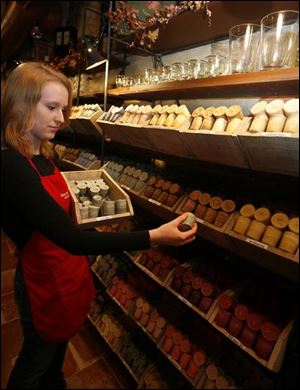 Store employee Meghan McCarthy fills bins with scented candles.