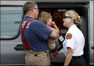 Toledo firefighter Joe Clark and Battalion Chief Chris Davis comfort Karis Thomas, 2, who was a passenger in a van that was involved in a May 31 traffic accident in West Toledo.