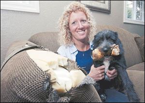 Kris Rockman and her dog, Cinder, with just one example of Cinder's handiwork, a torn sofa.