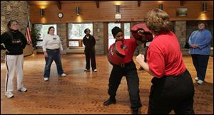 Susan Shelton of Maumee, in background from left, and Debbie Porter of Monclova join other class members in watching trainers Gail Awls and Becky Woodcock demonstrate some moves on the defense system during a session at Oak Openings Lodge in Swanton.