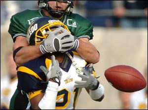 Eastern Michigan receiver Eric Deslauriers makes sure that Toledo cornerback Nigel Morris can't make an interception, but the Rocket did break up the pass in the end zone.