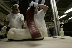 Bob Cooper, left, and Charles Smith add the stripe of color to a 20-pound log of candy.
