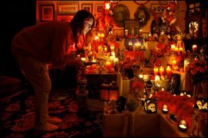 Kirsten Snodgrass lights all of the candles in her Day of the Dead display in her South Toledo living room.