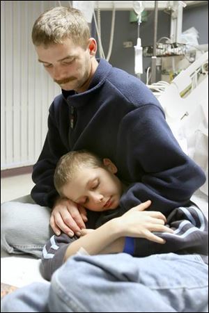 Trent Cousino hugs his son, Javan, 10, in a room at St. Vincent Mercy Medical Hospital as he talks about their tale of survival in Maumee Bay.