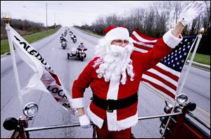 Larry Wulf, dressed as Santa, leads more than 800 motorcycles down Alexis Road on a mission to deliver toys to children.