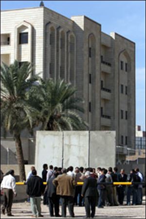 Iraqis gather at the gate of an education ministry office in Baghdad where gunmen kidnapped up to 150 people. Five officers were arrested.