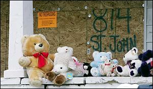 A memorial of stuffed animals lines the porch at 814 St. John Ave., where four people were killed in a fire Saturday. Two of the victims were children, Jamal McCollum-Myers and Sanaa Thomas.