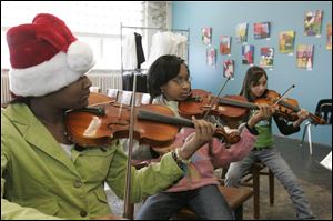 Practicing violin during an orchestra class at Toledo School for the Arts are, from left, Chafika Simmons, Richara Goss, and Taylor Ramos. The school is on 14th Street, near downtown.
