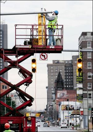 City workers hang a traffic signal at the intersection of 14th Street and Jefferson Avenue.