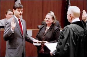 Newly elected Toledo Councilman Joe McNamara is administered the oath of office by Andy Douglas, right, as Mr. McNamara's mother, Jill Kelly, holds the family Bible. Mr. Douglas, a former Ohio Supreme Court justice, defeated Mr. McNamara's father, the late Dan McNamara, for a council seat in 1973. 
