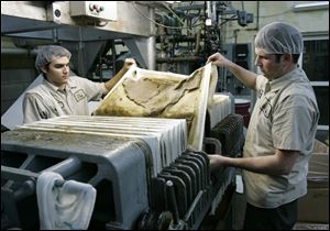 Tim Heiges, left, and Aaron Lipp remove fi ltering paper before bottling.