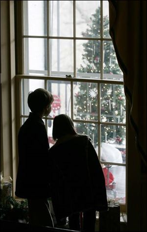 Ben Grant, 9, and his sister, Jillian Grant, 6, of Maumee take a peek at a holiday scene through a window
at the Manor House.