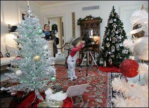 Kari Sweeney gets into the spirit of the  Snapshots of Christmas Past  display as her mother, Kathi Sweeney, left, watches.

