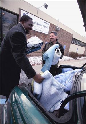 Richard Langford, director of the Mildred Bayer Clinic, and Harlan Joelson unload blankets for the Wrap Up Toledo campaign.