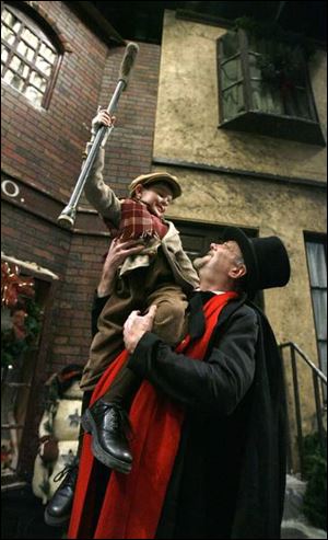 Paul Causman as Ebenezer Scrooge hoists Alexander Keck as Tiny Tim.