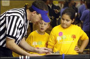 Referee Jeff Smith talks to Douglas Pienta, center, and Lydia Vergara about the score of their robot s performance. Douglas and Lydia are students at West Side Montessori Center.