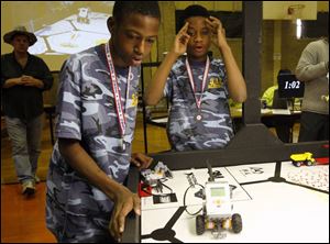 Eighth-graders Kyle Hueston, left, and Caleb Edwards of St. John s Jesuit Academy watch as their robot,  Sparky,  navigates during the competition at the Toledo Technology Academy.