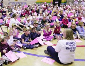 Teacher Dawn Mikolas applauds Rossford's Indian Hills students who read in a bid for a world record. Kindergartners Catherine Owen, left, and Matt Woycitzky were among about 320 students and staff reading a passage from 'Charlotte's Web.'