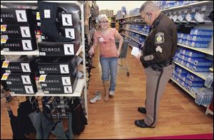 Kalynn Engels, 12, has one foot in a new pair of boots she would like to purchase at the Central Avenue Wal-Mart as Sylvania Township Police Sgt J.J. Barko checks the tally of gifts to see if she can get them within her $100 limit in the Shop with a Cop.
