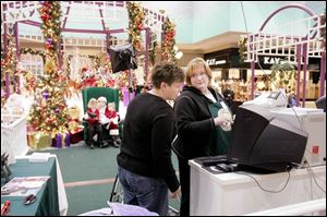 Anji Grant checks Tami Zunk's computer screen to select a photo of her daughters at Woodville Mall.