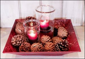Candles may be displayed in a variety of ways to give homes a special touch. Among the possibilities: in pairs in a festive dish with pinecones.