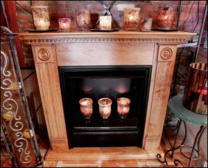 Candles in glass holders of various sizes are placed on a mantel and inside a fi replace at Swan Creek Candle Co.