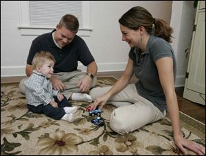Josh and Jessy Manuel play with son Caleb at home. Caleb was born with severe scoliosis, but recent surgery has allowed his radically curved spine to straighten significantly.
