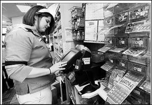 Cashier Jamie Snyder processes tickets for Friday s Mega Millions drawing at the Pilot truck stop on Libbey Road near I-280. The jackpot for the drawing was at $122 million yesterday.
