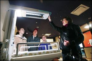 Jan Macmann, right, a registered nurse in the maternity ward, shows her family - from left, Allison, 12; husband Gary, and Julie, 10 - a state-of the-art infant warmer in the Well Baby Nursery at Blanchard Valley Hospital; star sparklets on the ceiling give the babies something on which their eyes can focus. 