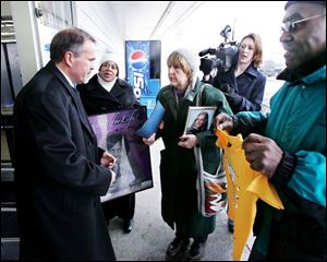 Past Rizzi, center, whose daughter was killed in a domestic violence incident, presents a folder with a letter and petition to a Kmart representative, left. An unidentified protester, right, holds one of the controversial T-shirts.