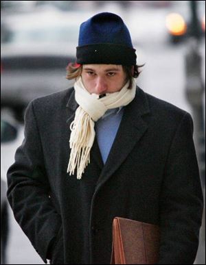 Justin Stone hunkers down in-side his coat, hat, and scarf to keep warm as he walks along Adams Street downtown.