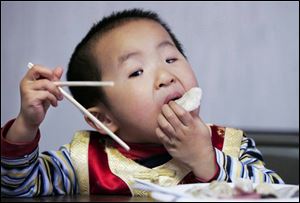 Harry Wang, 3, finds fingers are ideal for moving dumplings from the plate to his mouth at the New Year meal.