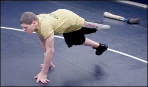 Napoleon s Brad Heinrichs does a bear crawl during wrestling practice after setting aside his prosthesis.
