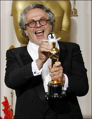 Holding a toy penguin, George Miller accepts the Oscar for Happy Feet.
