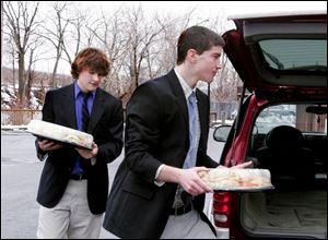 At left, Brendan McHugh and Kevin Blank, both students at St. Francis de Sales High School, carry food donated by Busia's Narozny restaurant into the reception area. Detective Dressel was an alumnus of St. Francis.