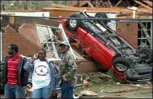 Residents gather near an overturned truck that landed against a house in Enterprise, Ala.