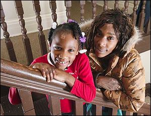 Aireana McClellan, 7, with her mother Latisha Miller in her sister's home on Elm Street.