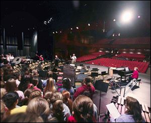 Retired Van Wert choir director Larry Schaufelberger, center, conducts student choirs in the 1,200-seat auditorium. 