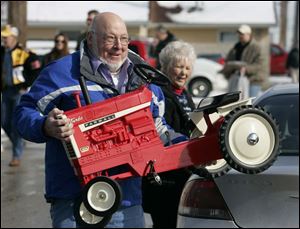 Fritz Vogel of St. Marys, Ohio, carries a pedal tractor purchased by Lucy Gray to her car. Ms. Gray is one of about 3,000 people expected for the Toy and Doll Show, which ends today at 3 p.m. 