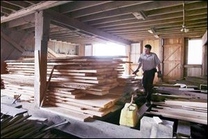 Andy Brown walks through the barn where he is stacking planks for a new wood floor to be installed inside a barn at Creek Bend Farm.
