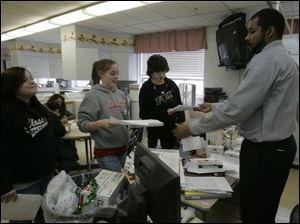 Glenn Green, right, checks the work of students Emily Blair, Katie Bollin, and Conor Morissey, left to right. Mr. Green, a substitute teacher, is the only black instructor in Bedford schools.