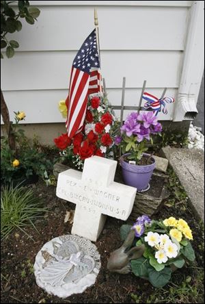 A white cross grave marker honoring Rex  Jack  Wagner is displayed in the front yard of his sister, Marilyn Patterson.