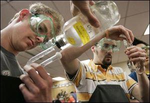 Alex Gilson, left, and David Grouls, both 18, pour potassium nitrate into a U-shaped tube that will serve as a salt bridge as they make batteries in Southview s advanced chemistry class.